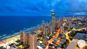 Un grand hôtel à plusieurs étages, situé près d’une plage et d’un plan d’eau.