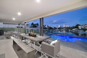 Un patio moderno al aire libre con piscina, mobiliario y vistas del horizonte de la ciudad.