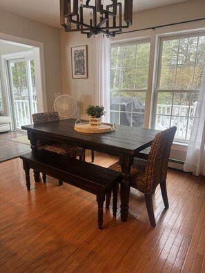 A dining area with a dark wooden table, woven chairs, and a bench. There is a fan and a potted plant on the table. - Private & Super Spacious, close to downtown N. Conway and ski. (Conway)