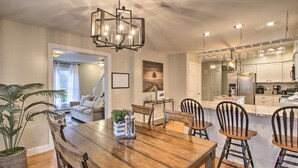 A dining area with a wooden table and chairs, a chandelier, and a kitchen in the background. - Private & Super Spacious, close to downtown N. Conway and ski. (Conway)