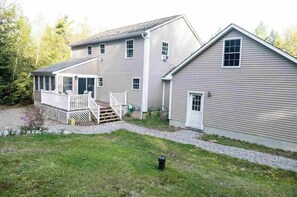 A two-story house with a covered porch and a separate garage. - Private & Super Spacious, close to downtown N. Conway and ski. (Conway)