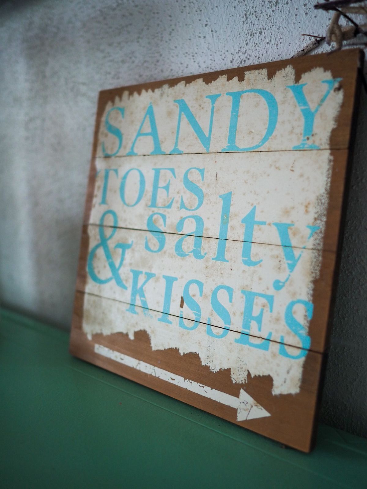 Une pancarte en bois sur laquelle on peut lire : « SANDY TOES SALTY & KISSES ».
