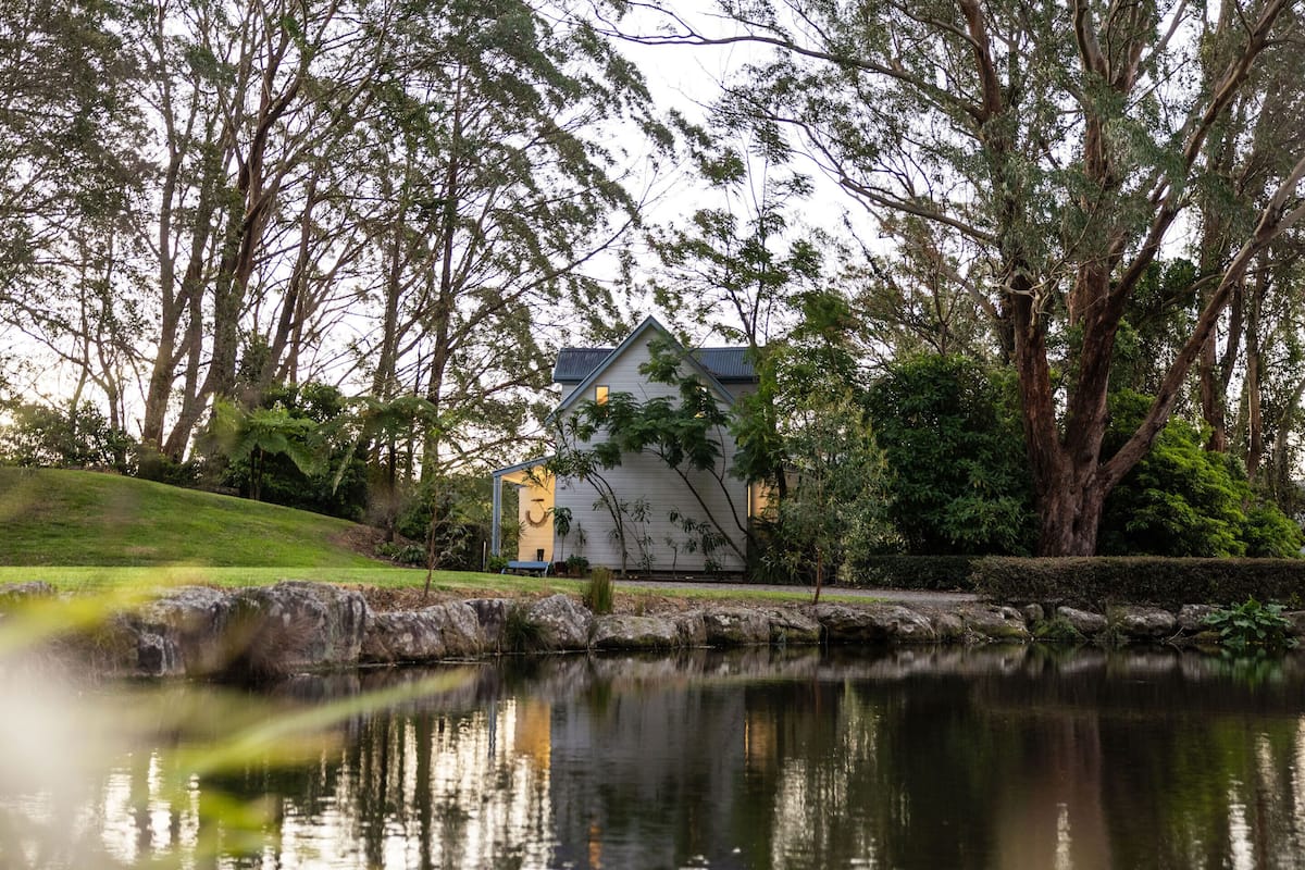 A house with a pond in front, surrounded by trees.