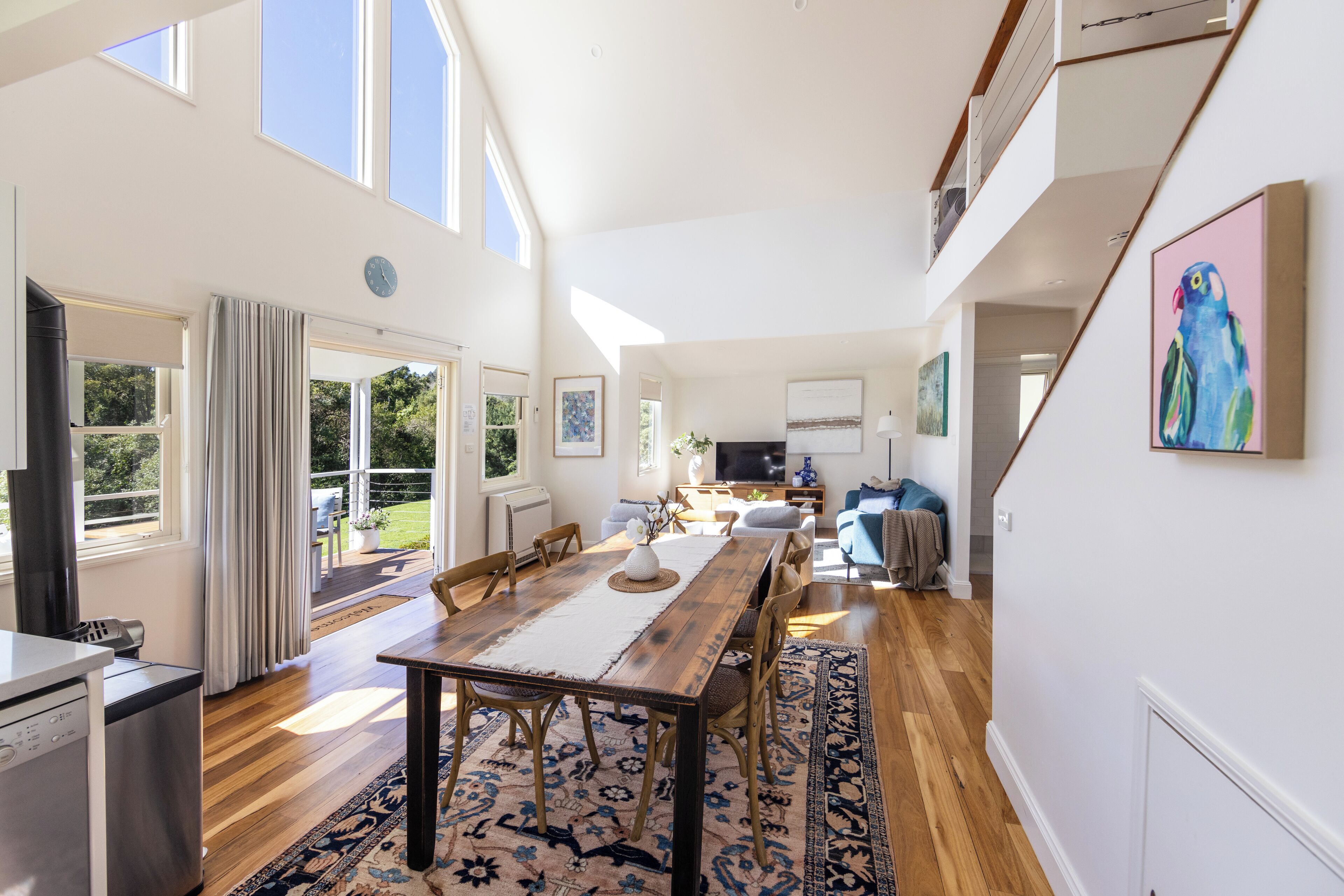 A spacious living area with a wooden dining table, comfortable seating, and a large window providing natural light.