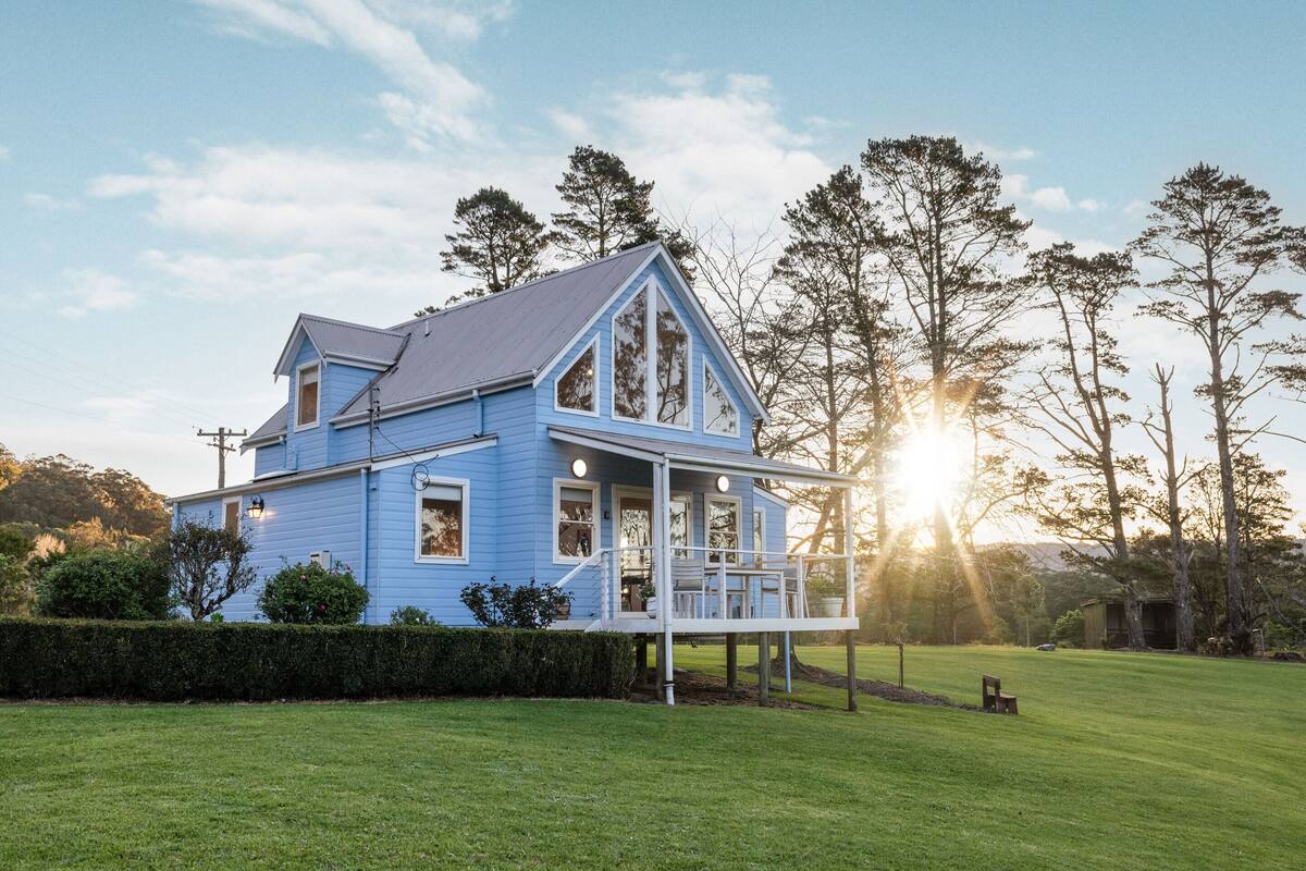 A blue house with a porch and a well-maintained lawn.