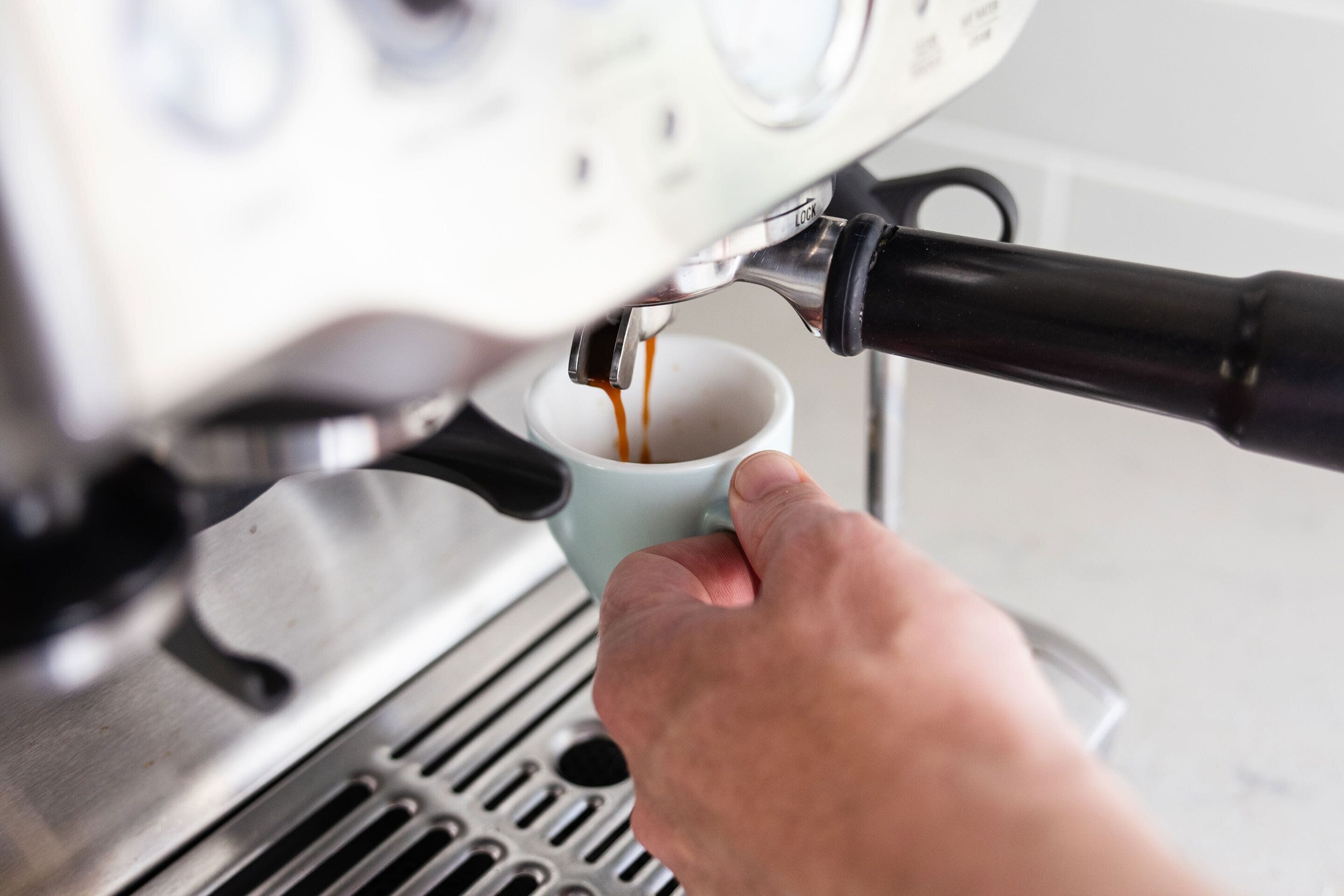 Une main tenant une tasse sous une machine à café.