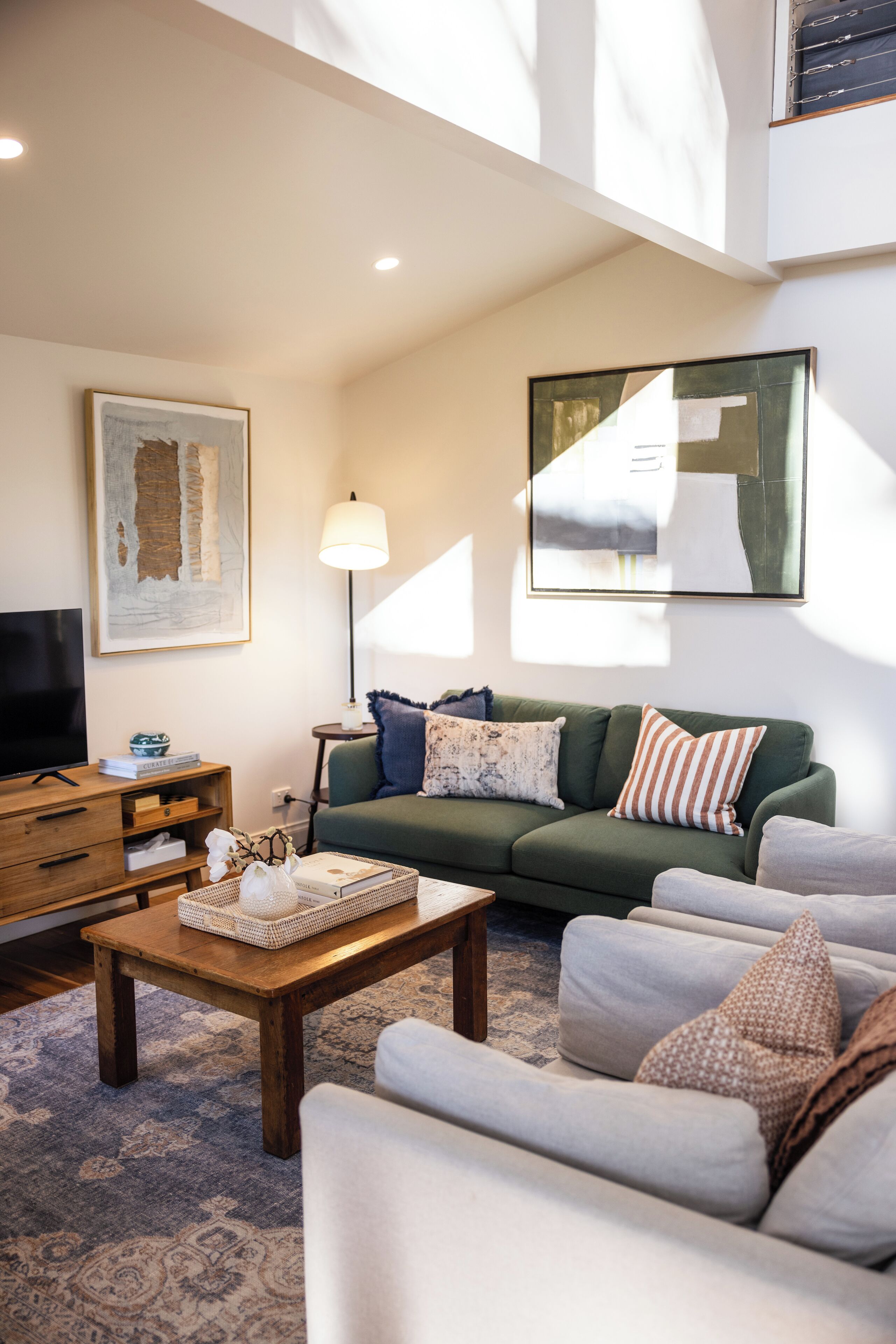 A living room with a green sofa, a wooden coffee table, and a TV on a wooden stand.