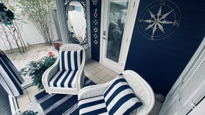 Une terrasse couverte, aménagée avec des meubles en osier et décorée d’une boussole.