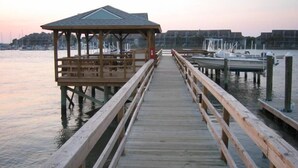 A wooden pier leading to a gazebo with a roof, extending into calm water with boats docked nearby. - Water's Edge 103 - Bright 3BR/3BA Townhome - Pool - Fishing Dock (Folly Beach)