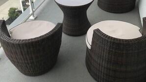 A balcony with wicker furniture and a view of a residential street.