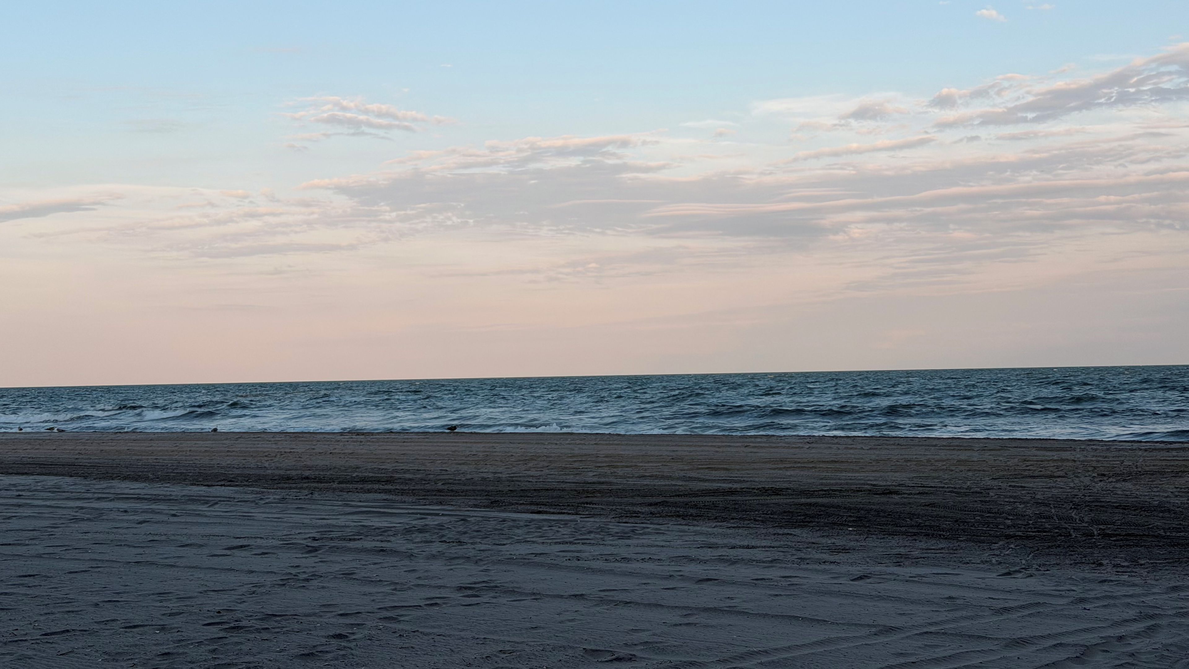 Uma praia com céu limpo e mar calmo.