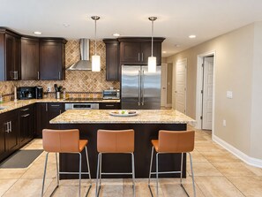 Une cuisine moderne avec des meubles en bois foncé, des appareils électroménagers en acier inoxydable et un plan de travail en granit.