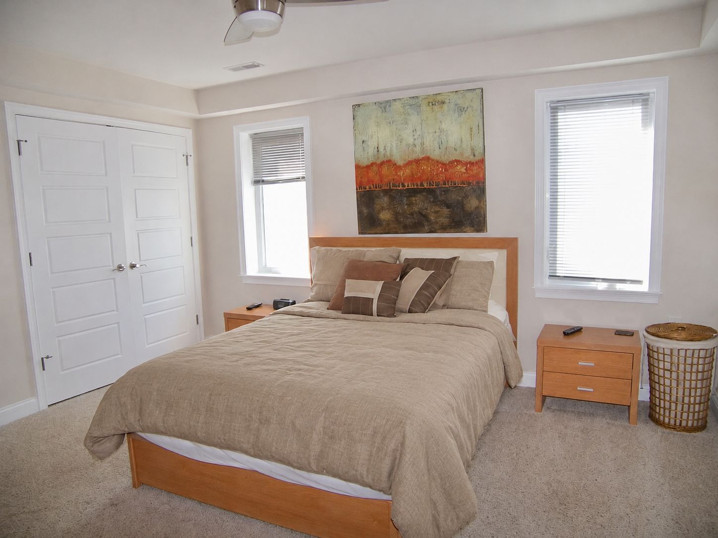A bedroom with a bed, nightstands, a wall painting, and a window.