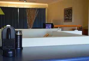 A modern kitchen with a coffee maker, a sink, and a window with curtains.