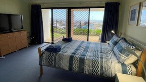 A bedroom with a bed, a TV, a dresser, and a view of the outdoors through a sliding door.