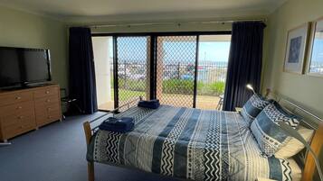 A bedroom with a bed, a TV, a dresser, and a view of the outdoors through a sliding door.