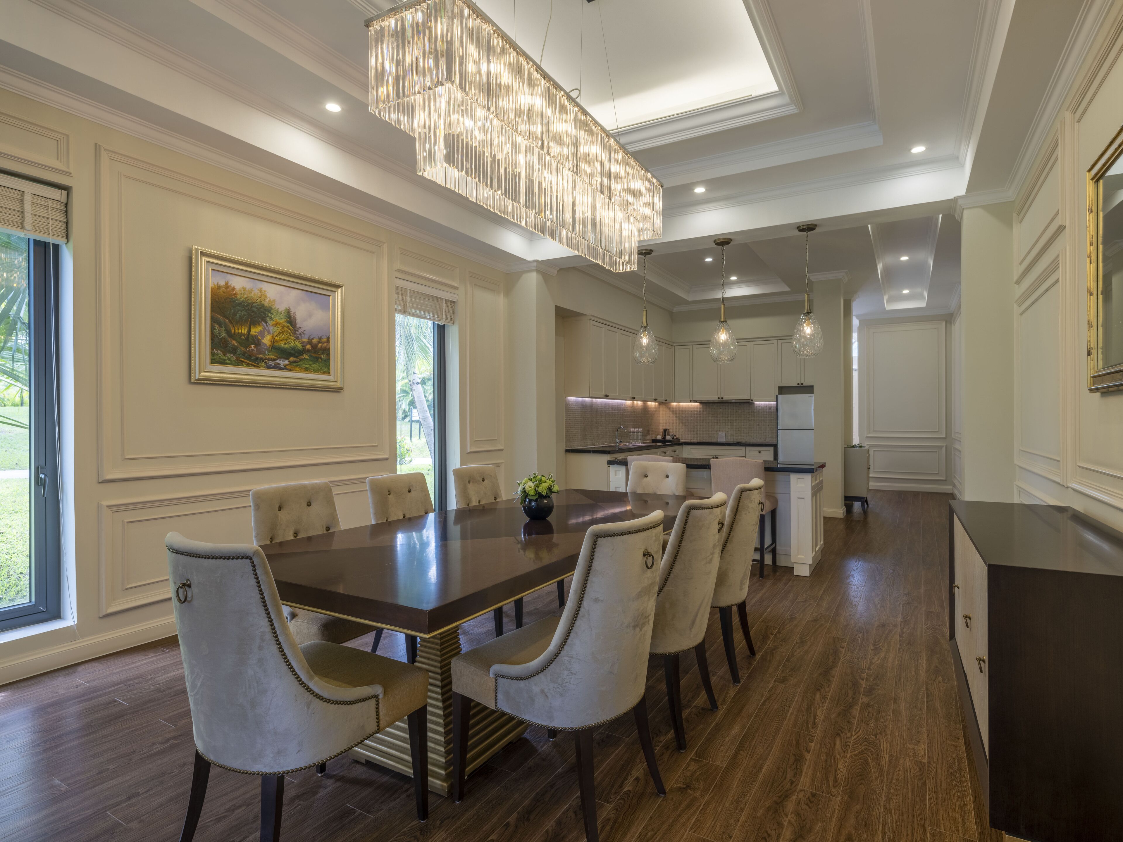 A spacious dining area with a long table, several chairs, and a chandelier.