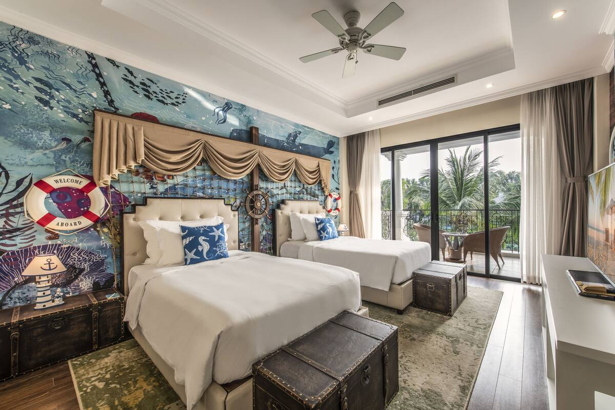 Een hotelkamer met twee bedden, een groot raam en een muurschildering met een nautisch thema.
