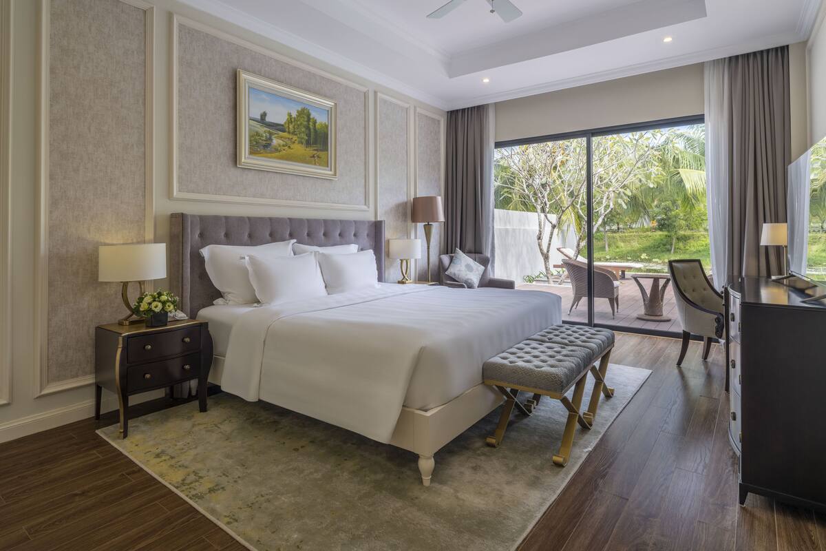 Een hotelkamer met een groot bed, een bureau, een stoel en uitzicht op het omliggende landschap.