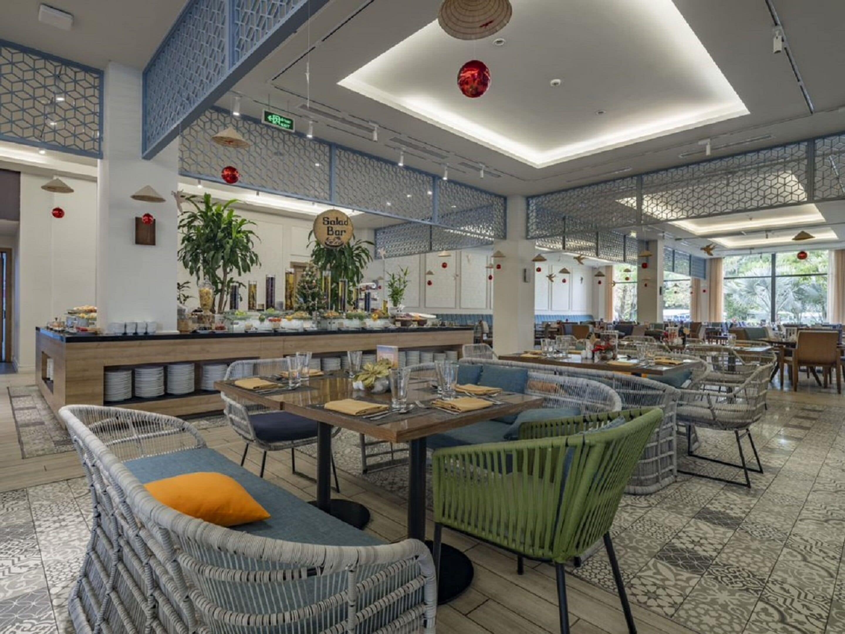 A spacious restaurant with high ceilings, a central bar area, and a variety of seating options including wicker sofas and chairs.