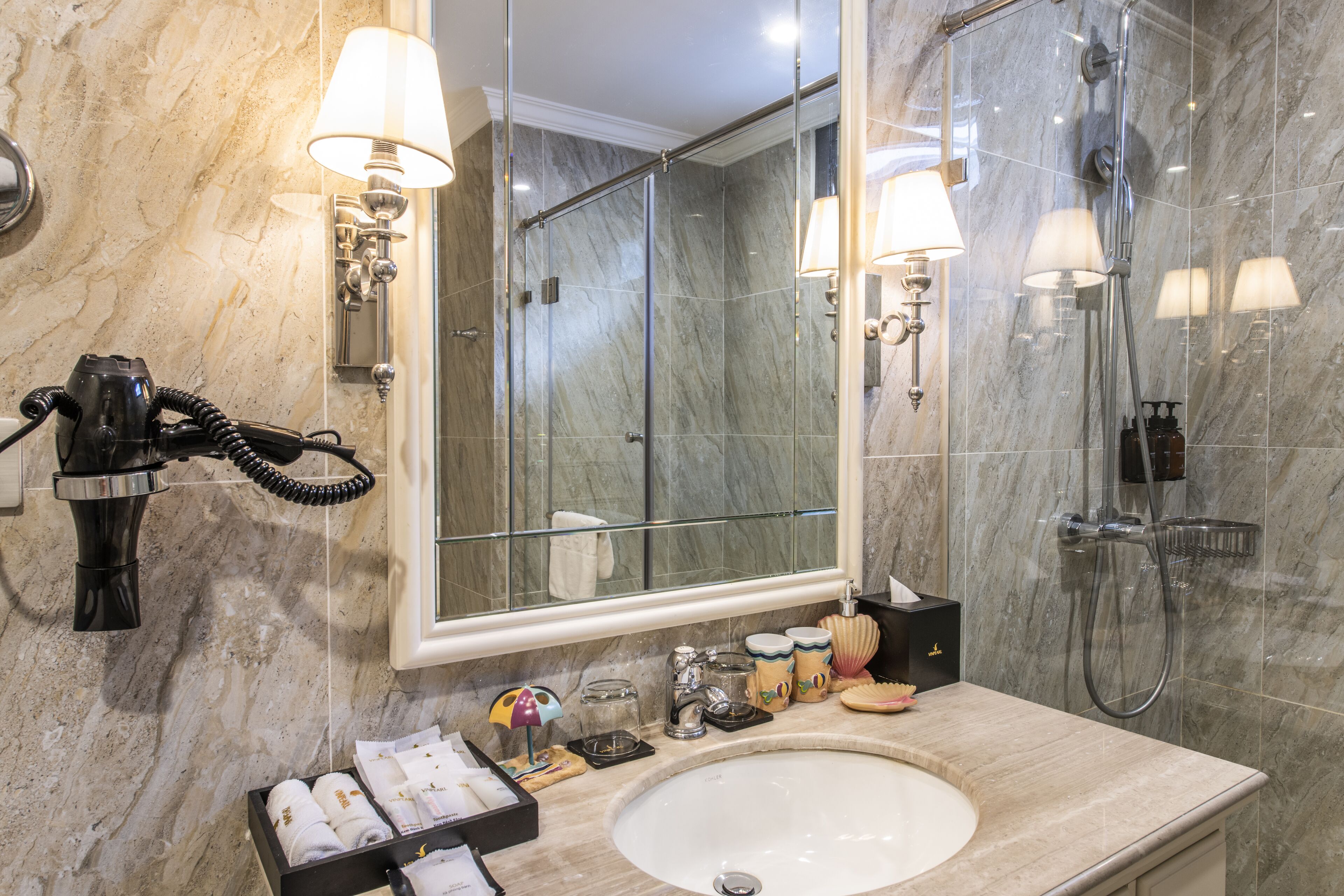 Une salle de bain moderne avec un lavabo en marbre, un grand miroir et une douche à parois de verre.
