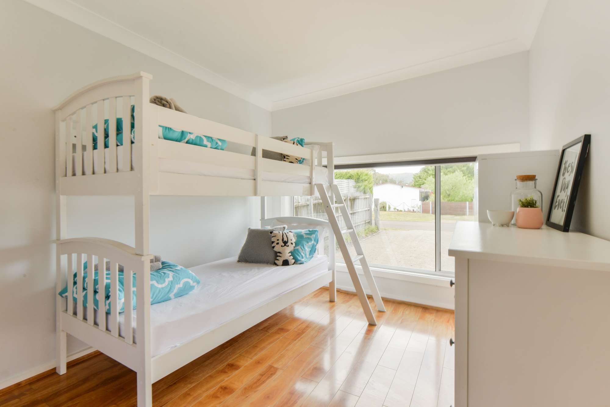 A bunk bed room with a desk and a window.