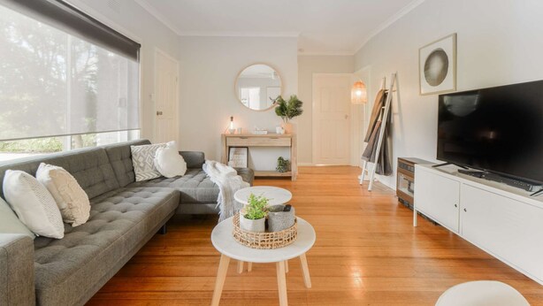 Un salon moderne avec un canapé gris, une table basse ronde, un téléviseur à écran plat et un ventilateur de plafond.
