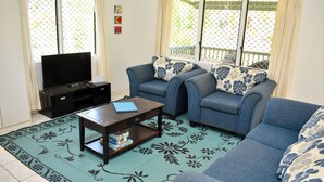 A living room with a sofa, a coffee table, and a TV. - Paere House, Snorkeling Heaven (Tikioki Beach)