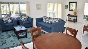 A living room with two blue sofas, a wooden coffee table, and a dining table with chairs. - Paere House, Snorkeling Heaven (Tikioki Beach)