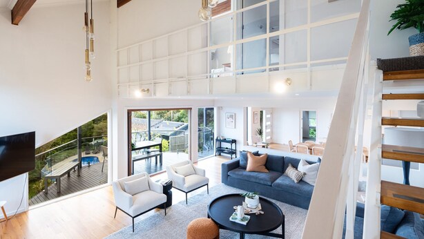 A spacious living area with a large window, a staircase, and a pool view. - Pet Friendly - Bay Views From Drury Lane with Solar Heated Pool and Gas Heated Spa (Dromana)