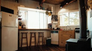 Een rustieke keuken met houten vloeren, een witte koelkast, een koffiezetapparaat en een fornuis.
