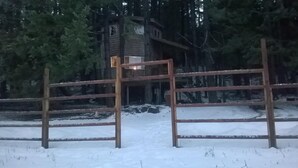 Een houten hek in een besneeuwd landschap, met een gebouw op de achtergrond.