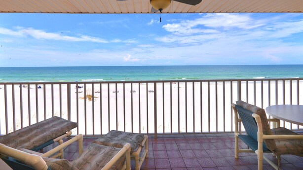 A covered outdoor area with a ceiling fan, a table, and two lounge chairs. It overlooks a beach with a railing and the ocean. - Direct Gulf Front Beach Paradise! Any Closer To The Water & You Would Be In It.. (Indian Shores)