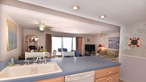 A kitchen with a blue countertop, white sink, and wooden cabinets. There is a ceiling fan, recessed lighting, and a dining area in the background. - Direct Gulf Front Beach Paradise! Any Closer To The Water & You Would Be In It.. (Indian Shores)