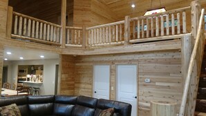 Een ruime inrichting met een houten balkon, een eethoek en een woonkamer met een leren bank.