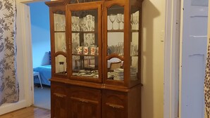 Un aparador de madera con puertas de cristal, que contiene diferentes vajillas y cristalería.