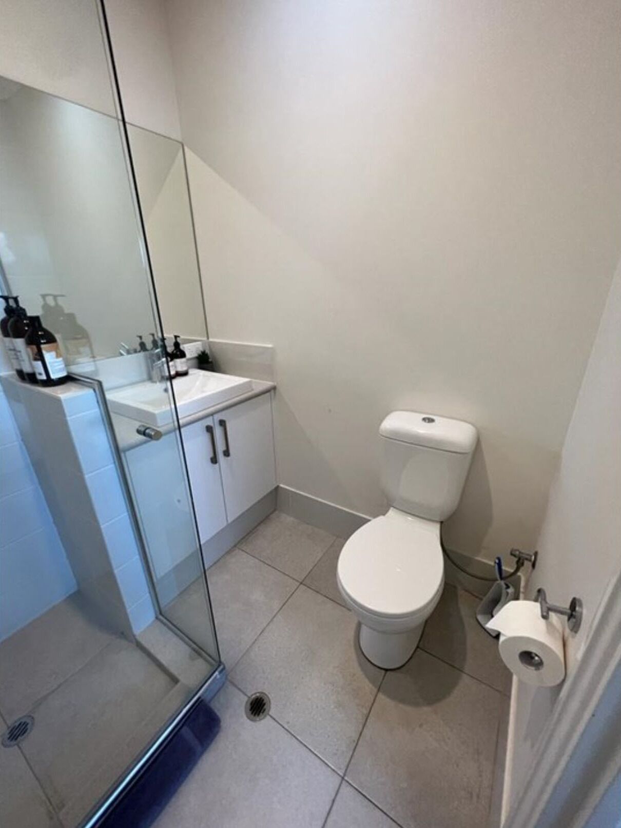 A bathroom with a toilet, sink, and glass shower enclosure.