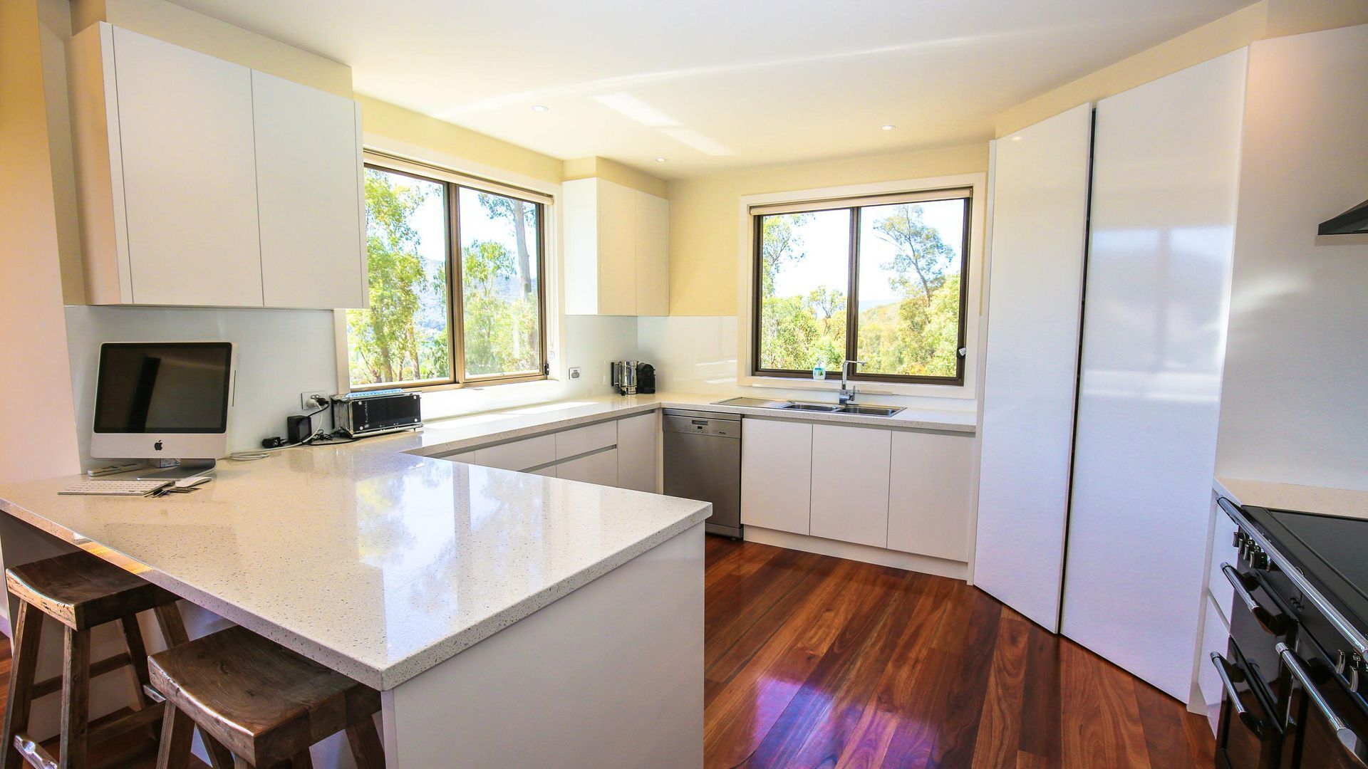 Una cocina moderna con una isla central, electrodomésticos integrados y ventanas amplias.