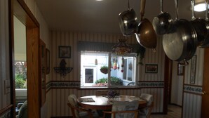 Un'area pranzo con un tavolo rotondo e sedie, una lampada a sospensione e una finestra con vista sull'esterno.
