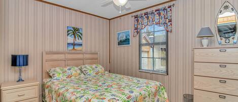 A bedroom with a bed, a nightstand, a dresser, a ceiling fan, and a window with blinds.