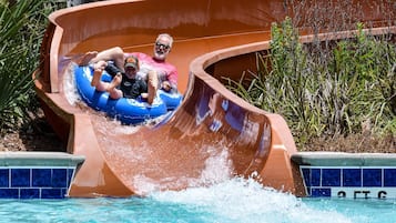 A water slide with a curved design, surrounded by a pool and greenery.