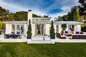 Une maison moderne dotée d’un patio, de deux arbres en pot et d’un coin repas.