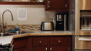 Une cuisine avec des meubles en bois, des appareils en acier inoxydable, une machine à café et un évier.