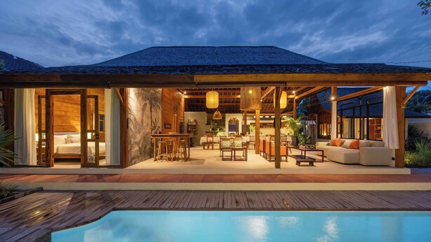 Una casa moderna con piscina, terraza de madera y zona de estar al aire libre.