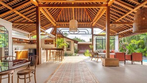 Un espacio interior amplio con techo alto, vigas de madera y una lámpara colgante en el centro.