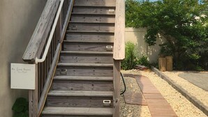 A wooden staircase leading to a building, surrounded by gravel and a wooden pathway. - OCEANSIDE Getaway: Affordable 3 Bedroom, Top Floor Apartment with Pickleball Fun (Long Beach Township)