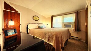 A bedroom with a bed, a clock, a lamp, and a window with blinds. - OCEANSIDE Getaway: Affordable 3 Bedroom, Top Floor Apartment with Pickleball Fun (Long Beach Township)