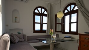 A modern living room with a glass-top coffee table, a sofa, and a wooden cabinet. - Breathtaking view, luxury, privacy, style and much more ! (Firostefani)