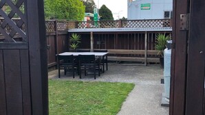 An outdoor patio area with tables and chairs, a gravel path, and a wooden fence. - The heart of Ohakune township with mountain views (Ohakune)