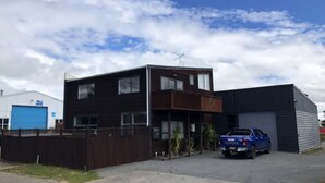 A modern two-story building with a dark exterior, a blue pickup truck parked in front, and a clear sky with clouds. - The heart of Ohakune township with mountain views (Ohakune)